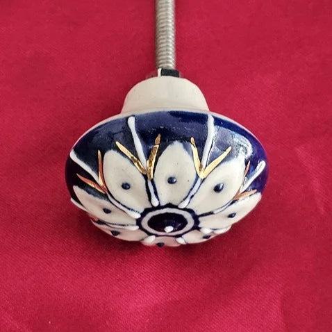 Blue and white ceramic knob with floral petal design and golden accents, handcrafted for vintage-style home furniture – Troika hardware collection.