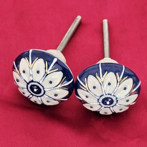 Pair of handcrafted ceramic knobs with blue background and white petal motifs, featuring gold detailing – vintage-style cabinet hardware by Troika.