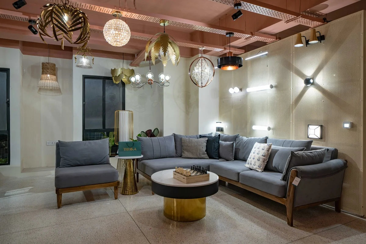 Interior lighting showroom featuring Troika’s designer lighting fixtures, sofa seating, and a mix of contemporary ceiling and wall lights – ambient home decor setting.