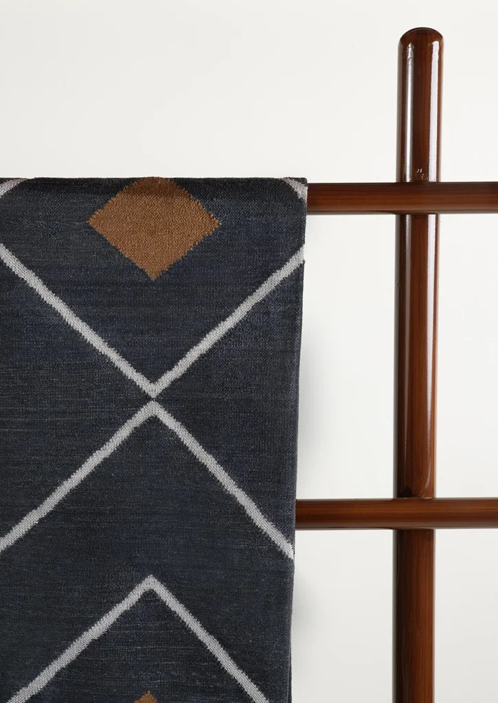 Close-up of the dhurrie focusing on the rust-colored diamond pattern and criss-cross white lines.
