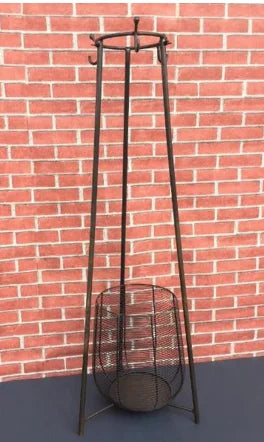 Full view of the tall iron stand with hooks and a wire basket base, set against a red brick background.