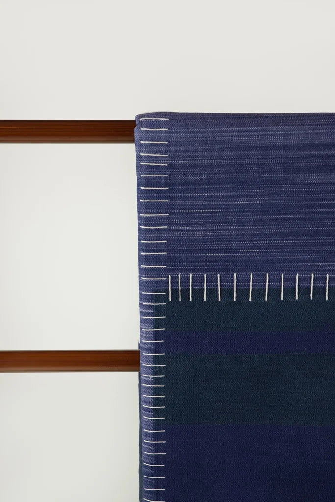 Close-up of Neel blue and navy block durrie artisanal craftsmanship with contrasting white stitch detail.