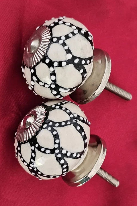 Pair of ceramic primrose knobs in white and black handcrafted drawer handles with metal accents.