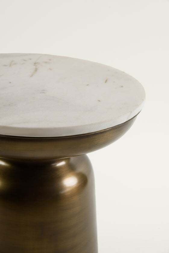 Close-up view of Aila table's white marble top and brushed brass base.