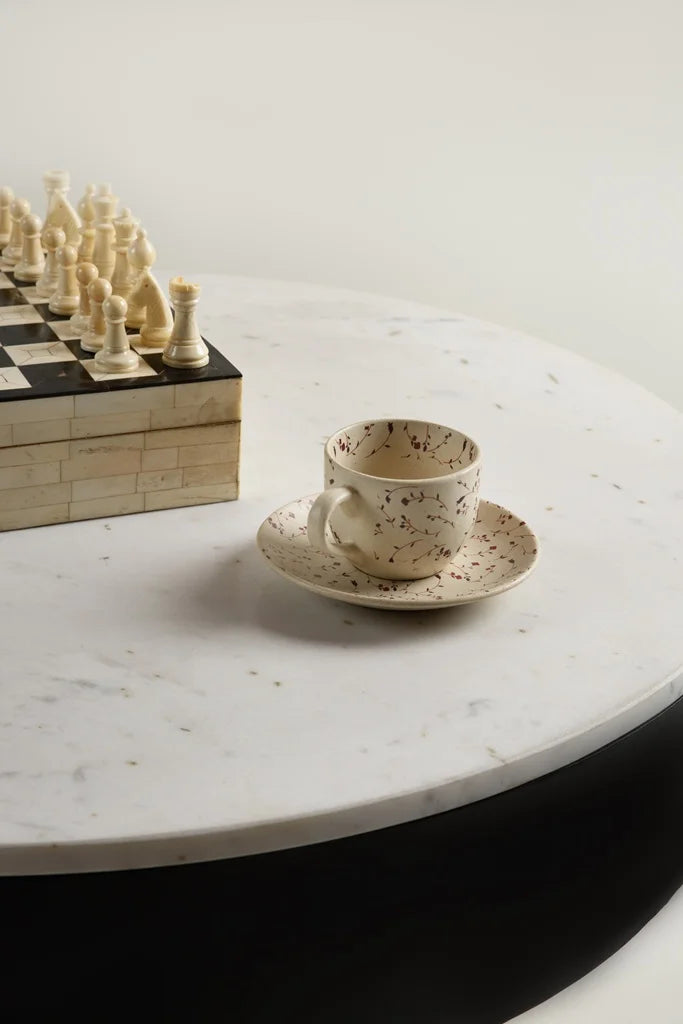 Modern round coffee table with marble top, chessboard, and ceramic cup in minimal setup