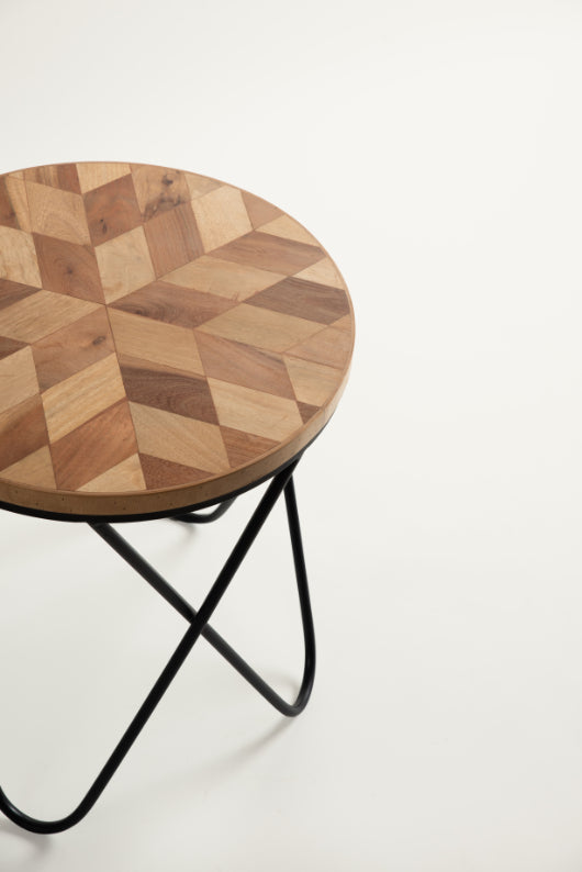 Stylish wood and iron side table with cup and jar on patterned surface.