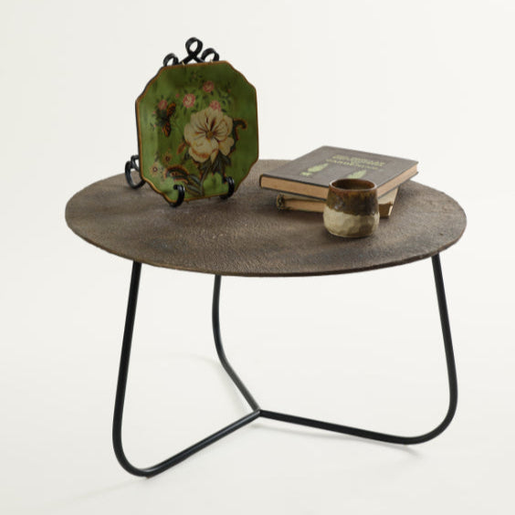 Rustic metal coffee table styled with green floral plate, stacked books, and a ceramic cup – curated Troika Life living room decor.
