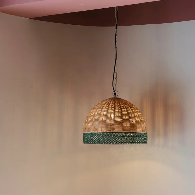 Dome-shaped rattan pendant light with green accent trim – artisanal hanging lamp for sustainable and earthy interiors.