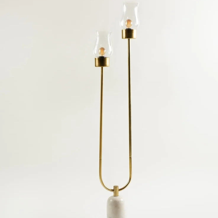 Sleek brass twin-light floor lamp with marble base minimalist style for luxury interiors.