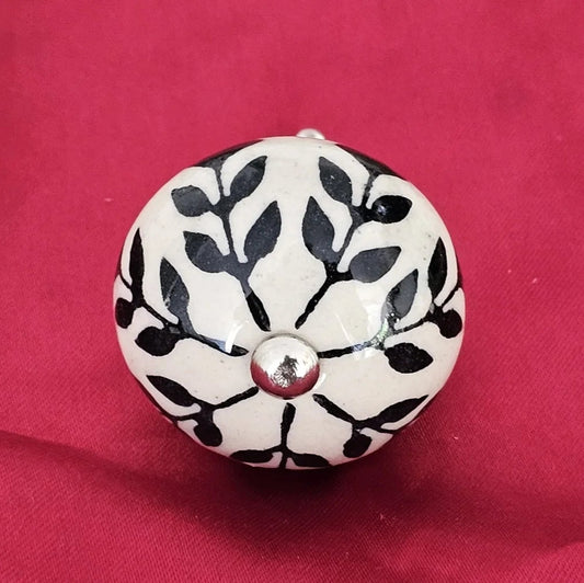 Single ceramic drawer knob with black floral vine design on white background, handcrafted home decor hardware by Troika.