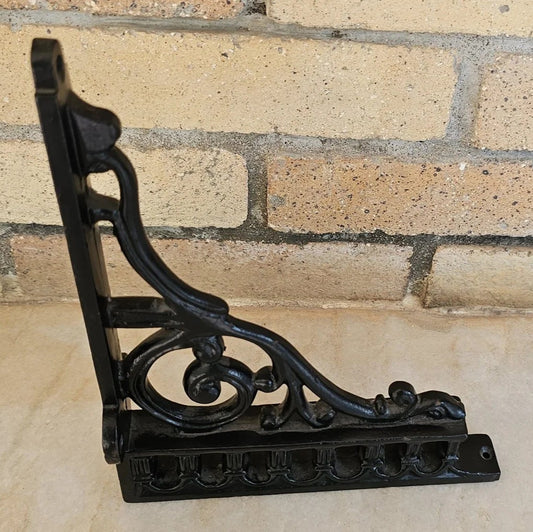 Black cast iron wall bracket with scroll design ideal for rustic shelves or hanging decor.
