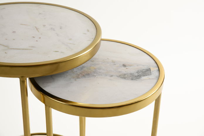 Closeup view of marble top on gold nesting table pair.