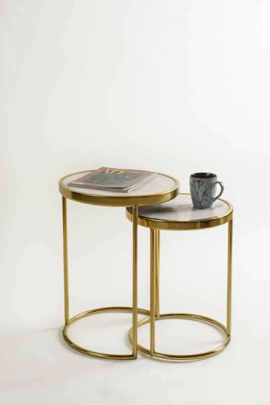 Decorative nesting tables styled with a magazine and ceramic mug on marble top.