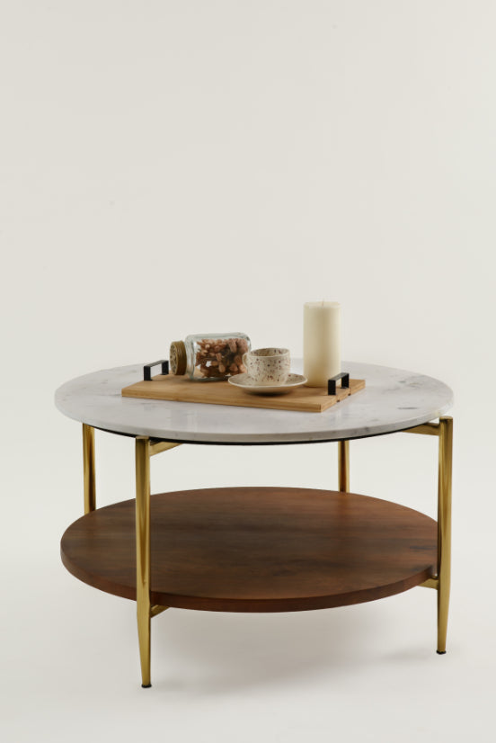 Round marble and wood coffee table with gold legs, styled with candle and tea set.