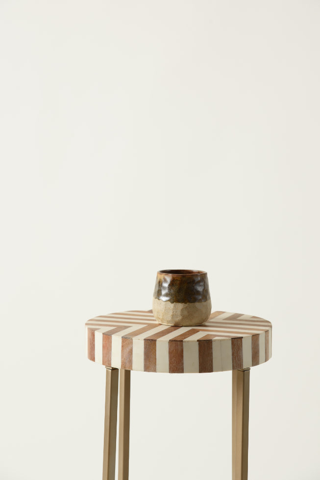 Bone inlay chevron table with decorative brown cup on top.