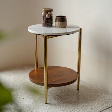 Compact round side table with white marble top and gold legs with wooden shelf.