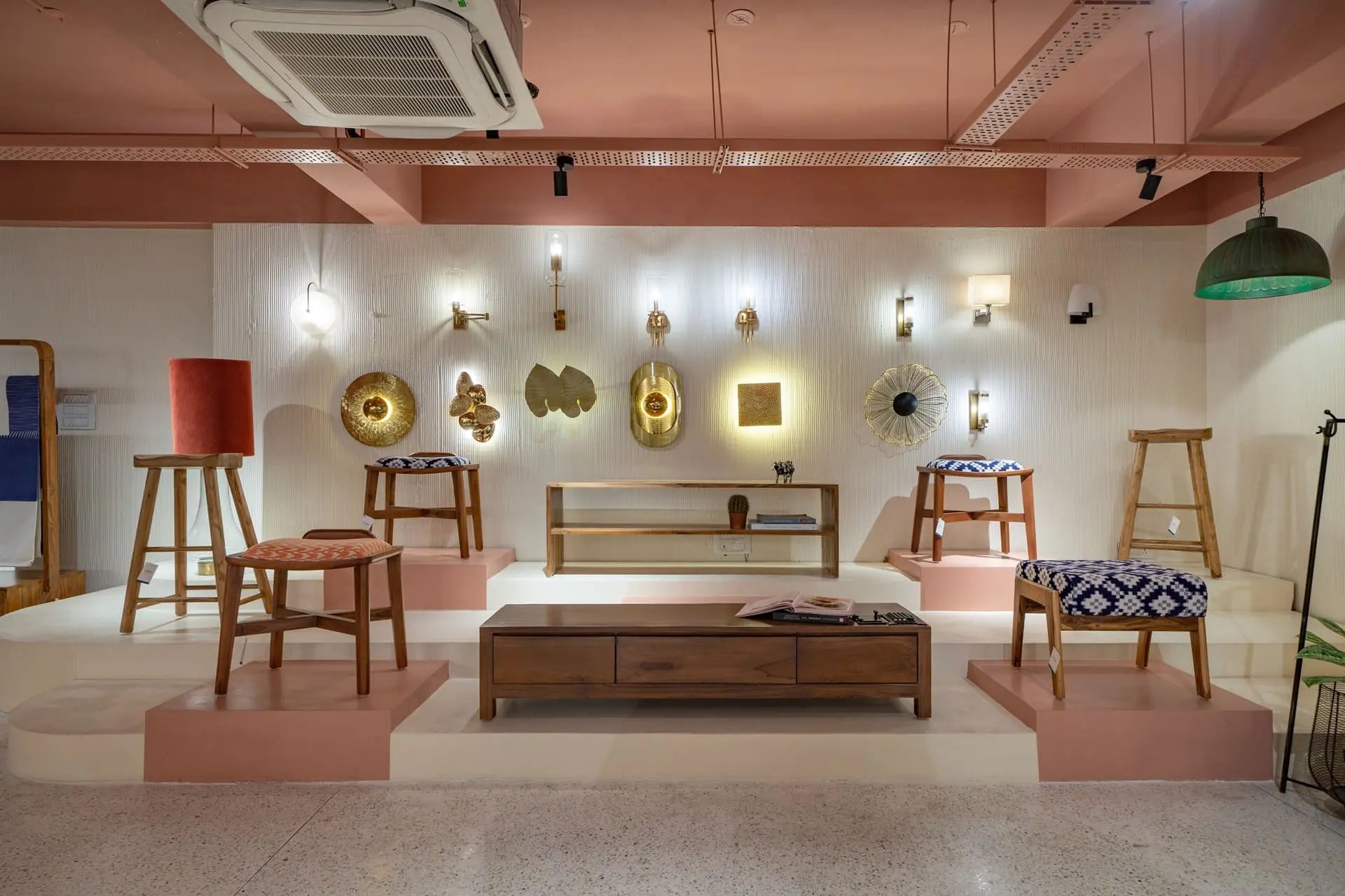 Interior showcase of Troika store featuring artisan wall lights, wood furniture and designer stools on display.