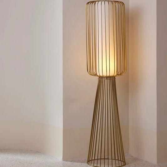 Tall modern floor lamp with cylindrical white diffuser and gold wireframe design, ideal for contemporary interiors – luxury lighting by Troika.