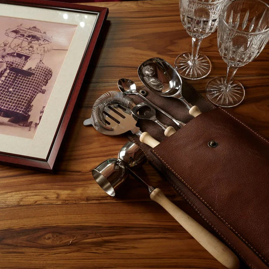 Vintage bar tool set in leather case with wooden handles, cocktail accessories laid out on wooden table – elegant barware by Troika.