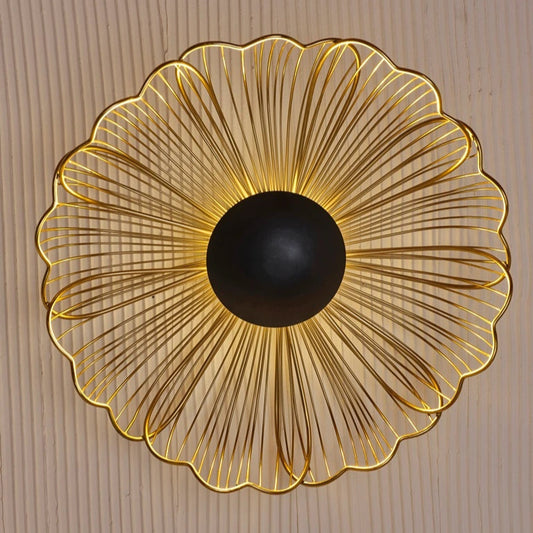 Wireframe floral wall light in golden metal with a central black hub. Radiates elegance and works well as a wall accent.