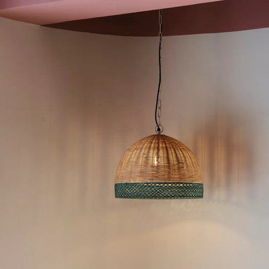 Dome-shaped rattan pendant light with green accent trim – artisanal hanging lamp for sustainable and earthy interiors.