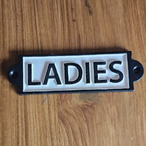 Vintage cast iron signboard labeled “LADIES” – black and white restroom door sign for public and private spaces.