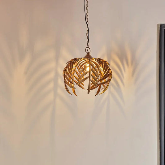 Artistic willow pendant light with cascading golden leaf blades and hanging chain, casting soft shadows